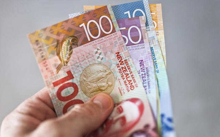 New Zealand currency held fanned out in someones hand