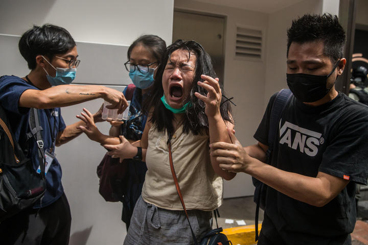 A woman who was hit with pepper spray deployed by police as they cleared a street with protesters rallying against a new national security law in Hong Kong on 1 July, 2020, on the 23rd anniversary of the city's handover from Britain to China. 