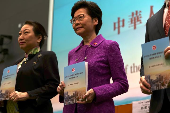 Hong Kong's Chief Executive Carrie Lam (C) poses with Justice Secretary Teresa Cheng (L) while holding copies of the new national security law during a press conference at the government headquarters in Hong Kong on July 1, 2020, on the 23rd anniversary of the city's handover from Britain to China. 