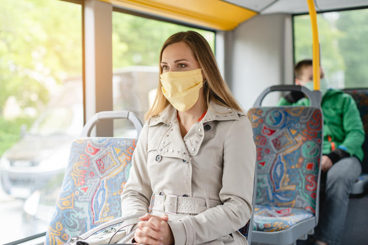 Woman using public transport during Covid-19 crisis wearing face mask.
