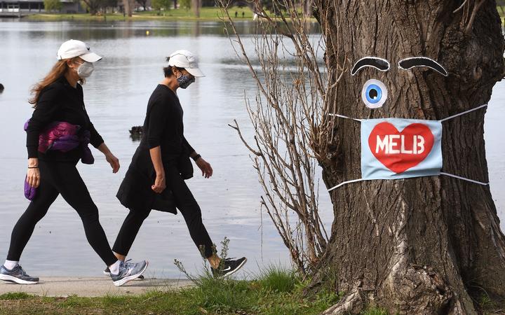 People wearing face masks exercise around the Albert Park Lake in Melbourne on August 26, 2020, as the city battles an outbreak of the COVID-19 coronavirus. 