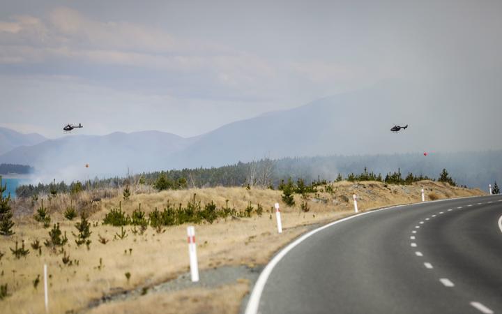 Two helicopters sweep overhead of the fire at Lake Pukaki in the MacKenzie District.