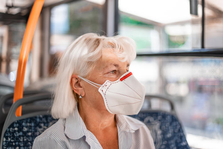 Caucasian woman in a protective mask sits in public transport at a distance of 2 m from other passengers. Protection and prevention covid 19, Coronavirus