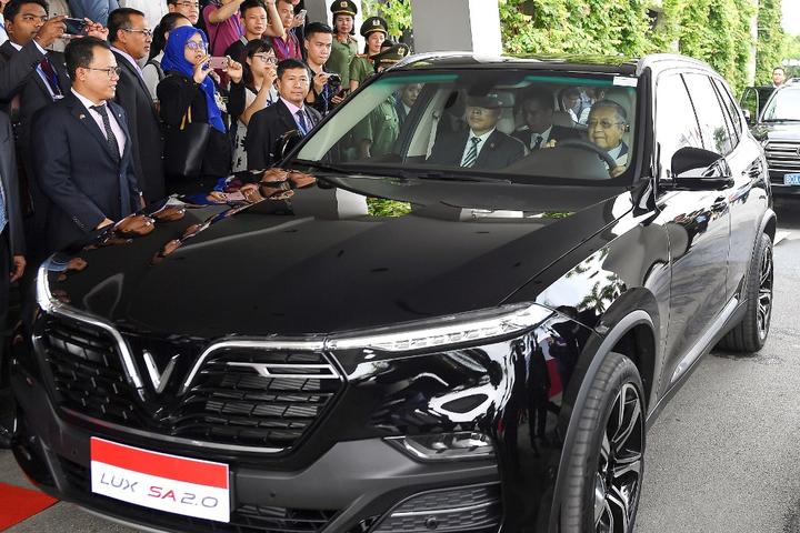 Malaysia's Prime Minister Mahathir Mohamad (R) drives a VinFast luxury SUV manufactured by Vietnam's first homegrown car manufacturer VinFast in Hanoi.