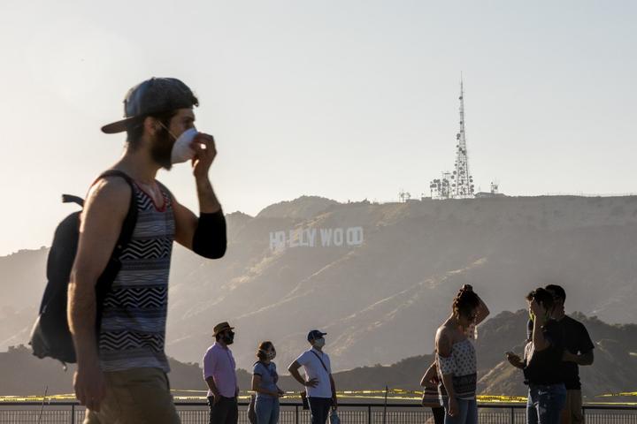 People wearing facemasks walk at the Griffith Observatory with a view of the Hollywood sign at the start of Memorial Day holiday weekend amid the novel coronavirus pandemic in Los Angeles on May 22, 2020. (Photo by Apu GOMES / AFP)