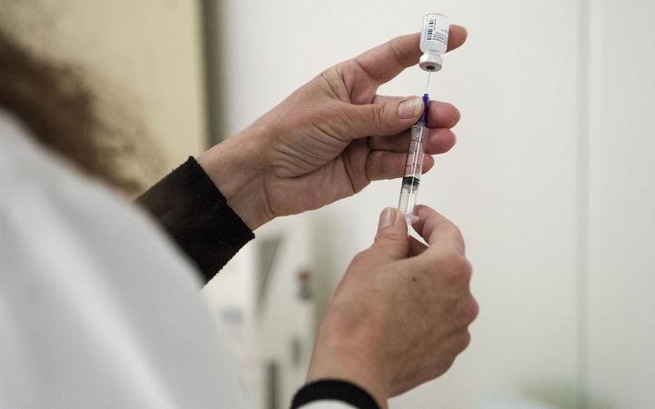 A healthcare worker launches a vaccination campaign at the Infectious Diseases University Clinic in Skopje on February 17, 2021, while a healthcare worker fills up a dose of Pfizer-BioNTech Covid-19 vaccine. 