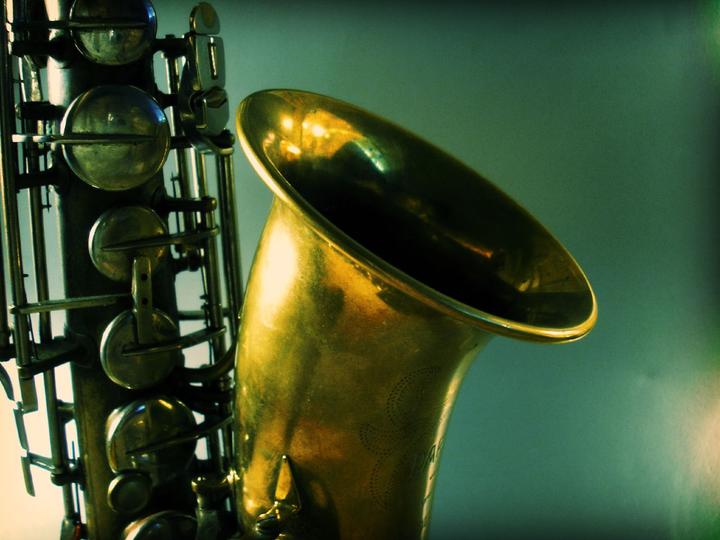 Artistic shot of a tenor saxophone on a blue-green background