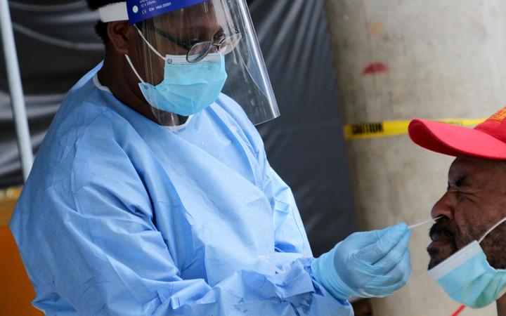 A health worker takes a swab from a man at a covid-19 testing centre in Port Moresby. 