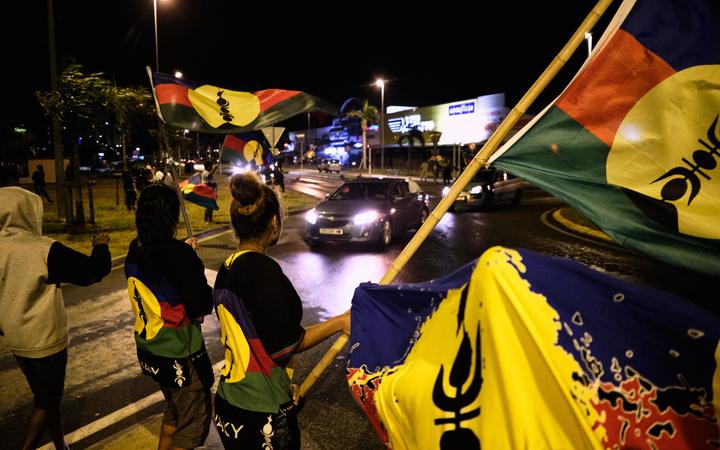 FLNKS supporters wave the Kanak flag of New Caledonia