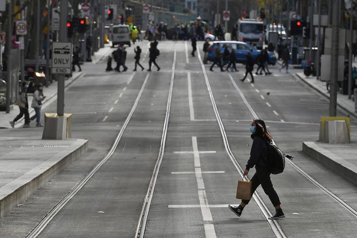 A shopper crosses the street in the central business district in Melbourne on July 7, 2021