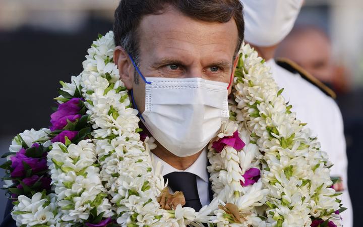 Le président français Emmanuel Macron est couvert de guirlandes lors d'une cérémonie d'accueil à son arrivée à l'aéroport international de Faa'a pour une visite à Tahiti en Polynésie française