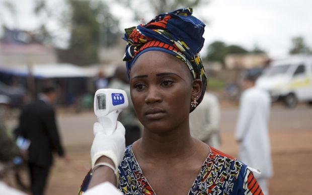 A health worker checks a woman entering Mali from Guinea  for signs of Ebola.