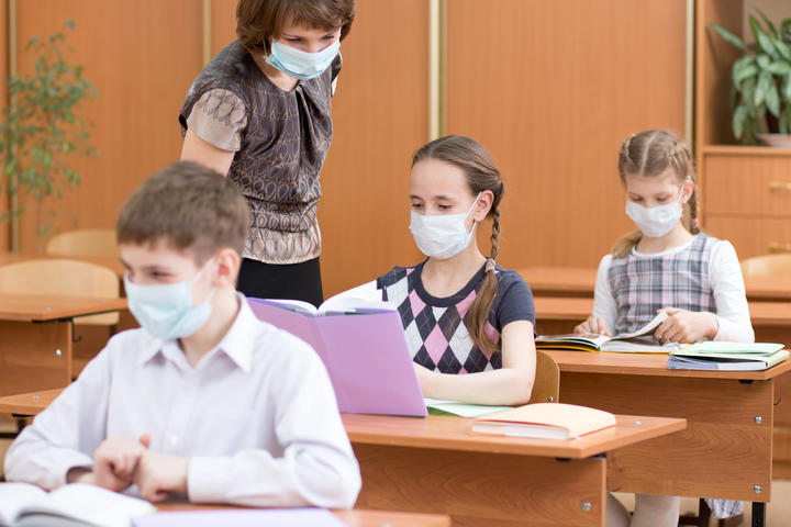 school children with protection masks against flu virus at lesson in classroom