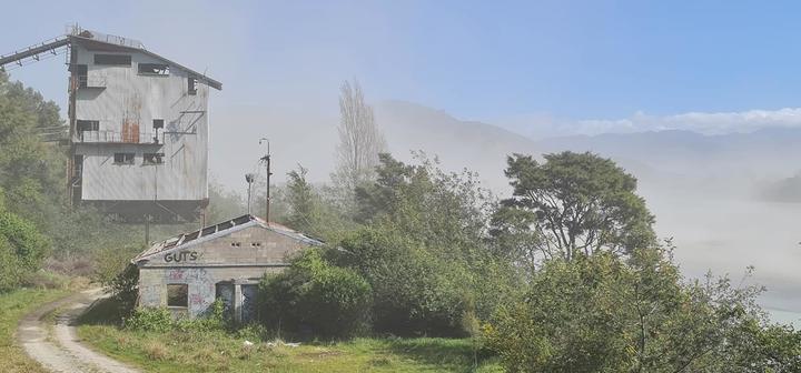A cloud of dust billows up around an old gravel processing factory next to the Waiapu River in Ruatoria.