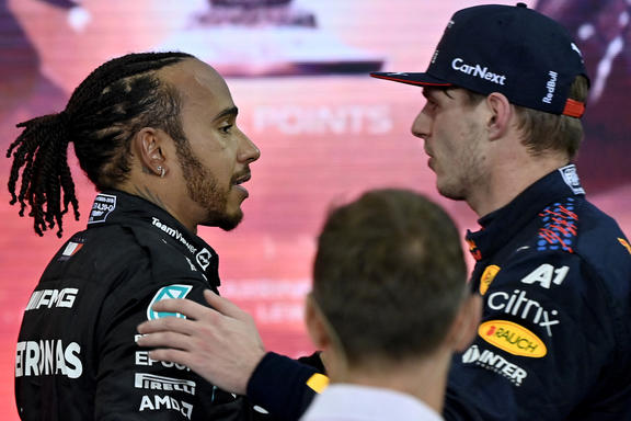 Nīderlandes braucējs Red Bull čempions Makss Verstapens (pa labi) sveic Mercedes britu pilotu Lūisu Hamiltonu pēc Abū Dabī Formula 1 Grand Prix izcīņas Yas Marina Circuit trasē 2021. gada 12. decembrī.