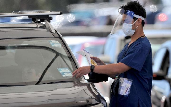 A health official collects a COVID-19 swab test at a drive-through testing site on Bondi beach in Sydney on December 15, 2021, as rapidly-growing Omicron and Delta clusters brought more than 2,700 new cases nationally.