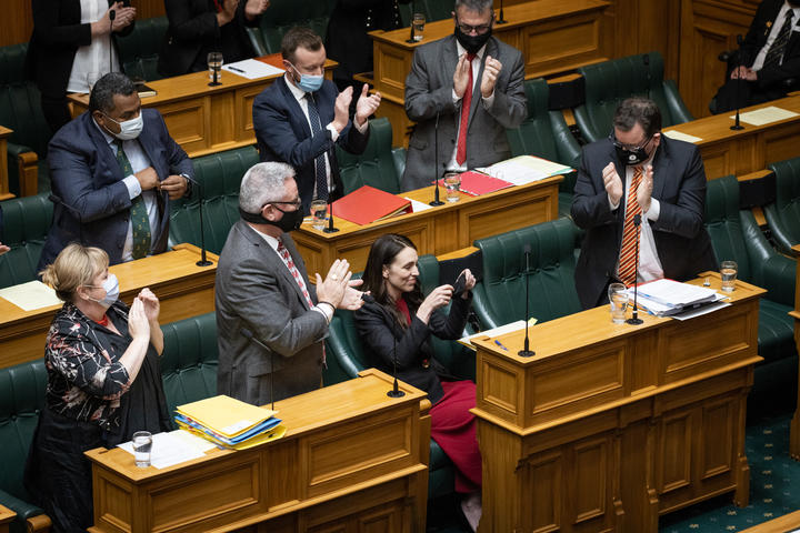 Jacinda Ardern puts her mask back on as her colleagues applaud her adjournment speech