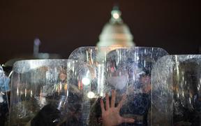 National Guard troops are seen behind shields as they clear a street from protestors outside the Capitol building on January 6, 2021 in Washington, DC. oup.