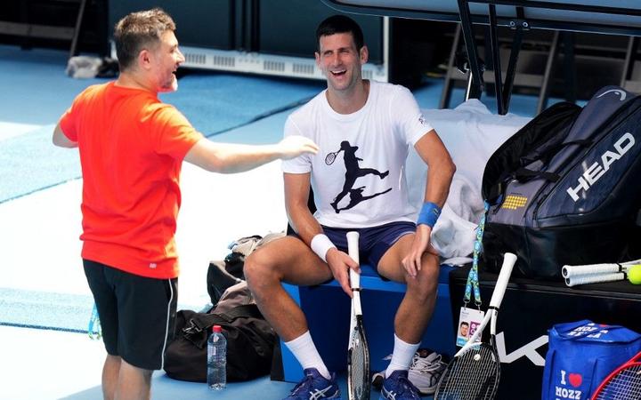 This handout photo taken and released by Tennis Australia on January 11, 2022 shows Serbia's Novak Djokovic (R) during a training session ahead of the Australian Open tennis tournament in Melbourne. 