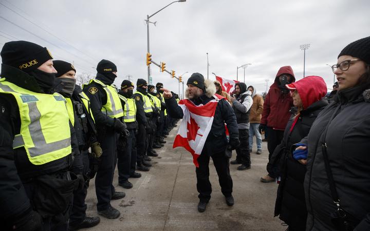 WINDSOR, ON - FEBRUARY 12: Protestors confront police as their try to clear protestors and their vehicles from a blockade at the entrance to the Ambassador Bridge, that was sealing off the flow of commercial traffic over the bridge into Canada from Detroit, on February 12, 2022 in Windsor, Canada.