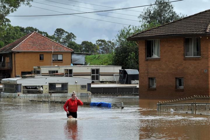 A resident fades through water in western Sydney on March 3, 2022, as the area faces its worst flooding after record rainfall caused its largest dam to overflow. 