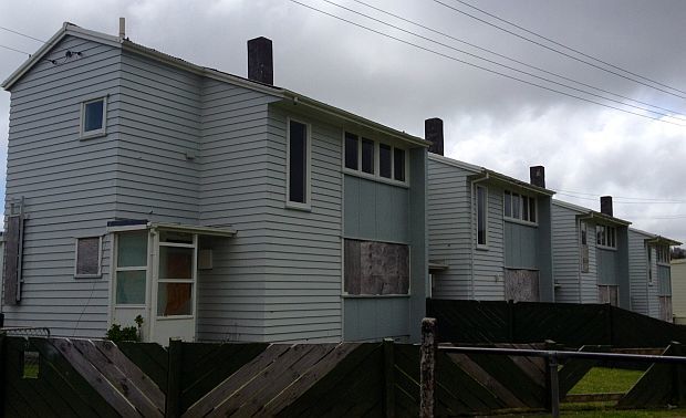 Row of two storey weatherboard houses with boarded up windows 