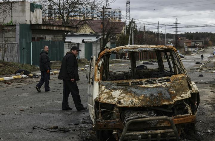 People walk through a street strewn with several dead bodies in Bucha, northwest of Kyiv.