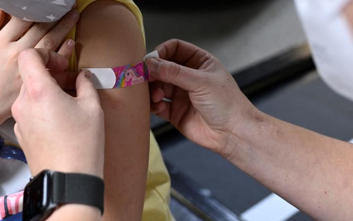 Six-year-old Hanna (L) receives a plaster after having been inoculated with the Pfizer BioNTech vaccine for children at a vaccination centre set up at a car dealership in Iserlohn, western Germany, on January 5, 2022, 