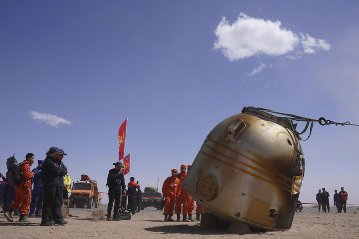 Officials stand near the capsule of the Shenzhou-13 spacecraft after it returned to earth carrying three Chinese astronauts in China's Inner Mongolia.