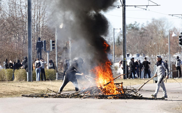 Protesters build a burning barricade on a street during the riots in Norrköping, Sweden on Sunday. 