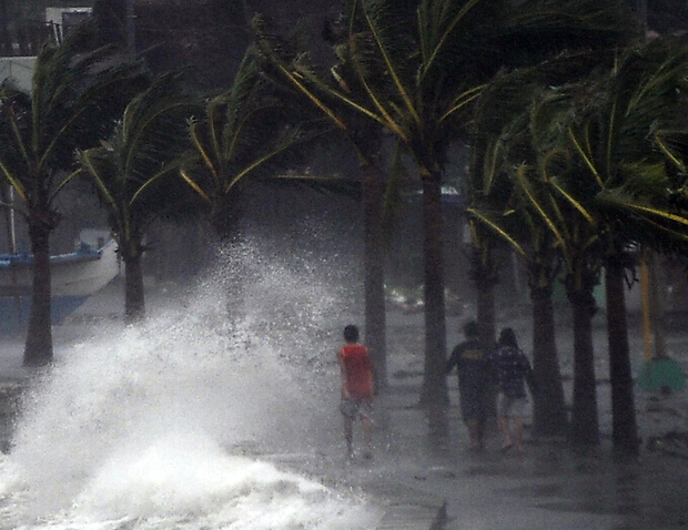 Residents walking past high waves brought about by strong winds pounding the seawall.

