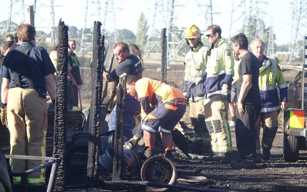 Firefighters help home owners sort through debris of house destroyed by fire.