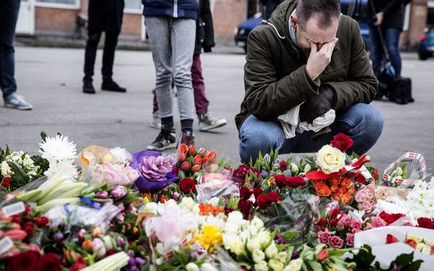 A man reacts next to flowers for the shooting victims outside the "Kruttoende" cultural centre in Copenhagen.