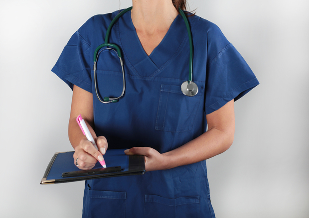  Doctor with a stethoscope writing on a clipboard.