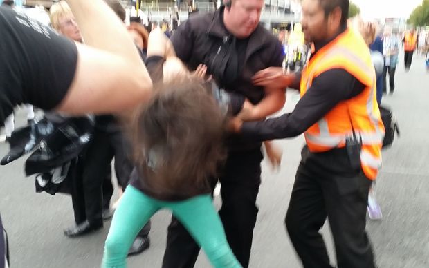 A woman protesting at Auckland's Pride Parade is handled by security guards.