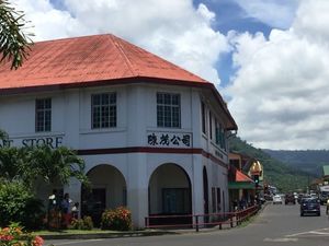 White 2 story Chinese supermarket in Apia, Samoa with terracotta tiled roof and Chinese signage. .