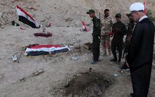 Iraqi Shiite fighters and members of Iraq's Popular Mobilisation, pray at a burial site believed to hold victims of a June massacre.