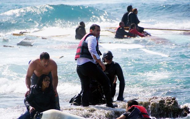 Local residents and rescue workers help a woman after a boat carrying migrants sank off the island of Rhodes, southeastern Greece, on April 20, 2015.