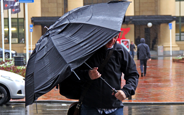 Commuter battles the horizontal wind and rain leaving Wellington Train Station.