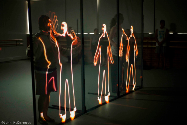 A production still from In Transit showing a dancer interacting with projected images.
