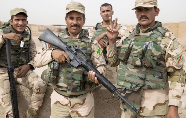 Four Iraqi soliders in full kit and armed line up for photos.