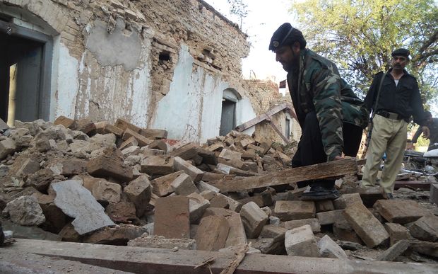 A Pakistani policeman digs through the debris of collapsed houses in Kohat.