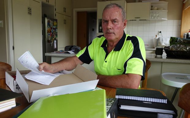 John Kerr sits at desk surrounded by files