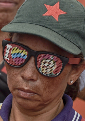 A supporter of Venezuelan President Nicolas Maduro wears glasses depicting the late former Venezuelan President Hugo Chavez.