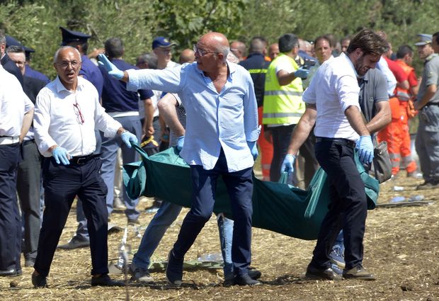 Rescuers carry a coffin after a head-on collision between two trains, near Corato, in the southern Italian region of Puglia on July 12, 2016.