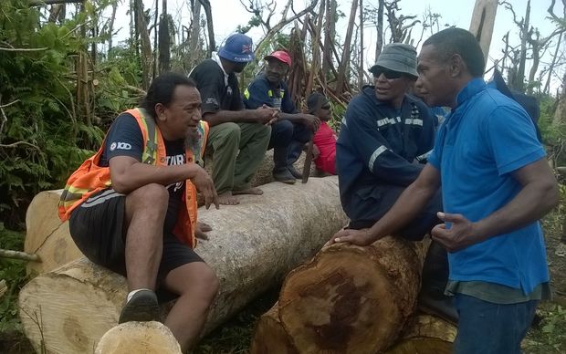 Itu Josaia (L) and the logging team take a break while dragging logs by hand in Nasau Village, Koro Island.