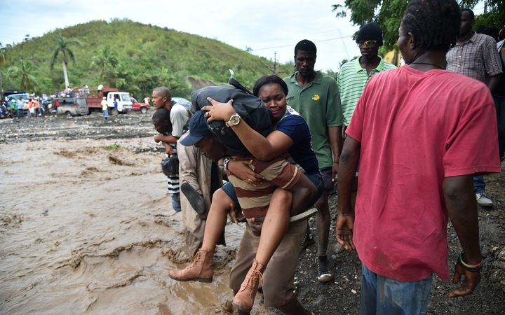 People in Haiti cross the river La Digue in Petit Goave where the bridge collapsed during the rains from Hurricane Matthew.