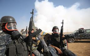Iraqi forces wear gas as smoke billows from a burning sulphur factory about 30km south of Mosul.