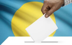 hand voting with Palau flag in background