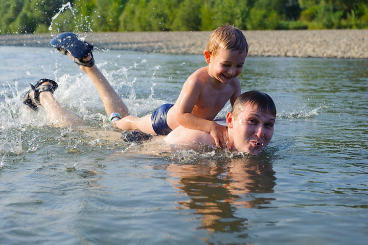 A father and his young son swim in a river (file) 